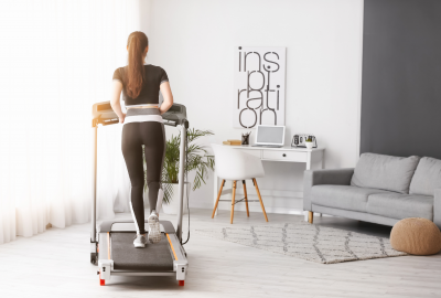 Imagem decorativa de uma modelo fazendo atividade física em uma esteira em casa, representando os aparelhos fitness silenciosos